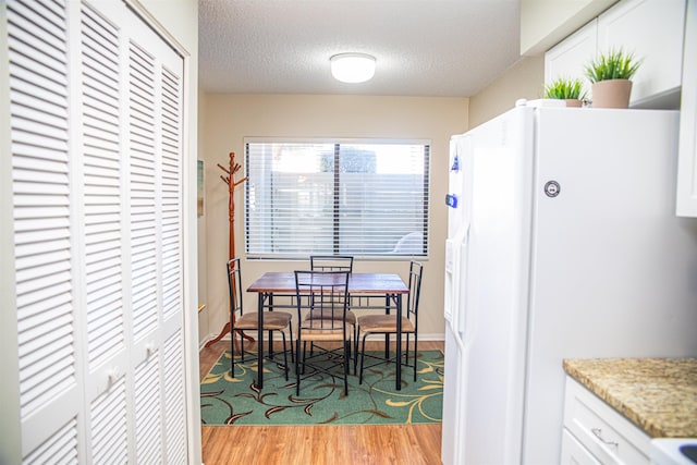 dining room with a textured ceiling and light wood-type flooring