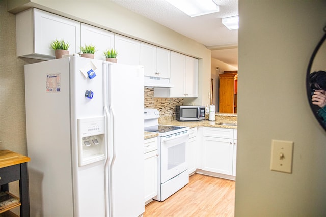 kitchen featuring white appliances, light stone countertops, light wood-type flooring, tasteful backsplash, and white cabinetry