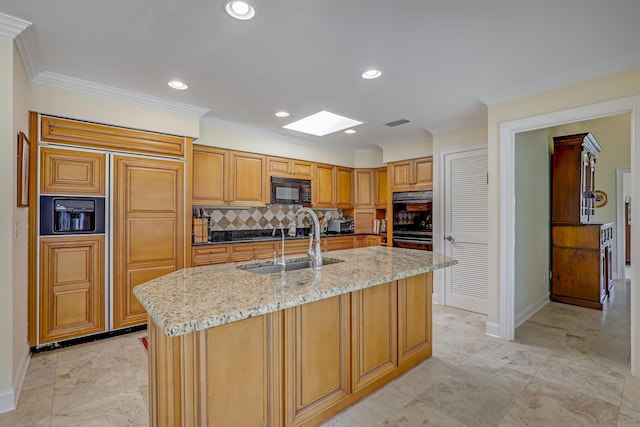 1 Sandpiper Cv, Ponte Vedra Beach, FL 32082 - kitchen with black appliances, a skylight, decorative backsplash, light stone counters, and a center island with sink