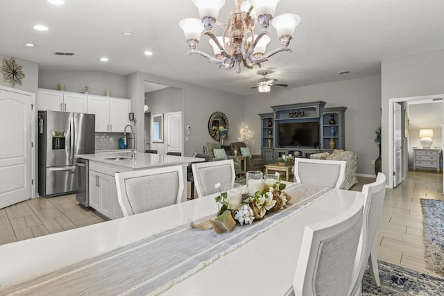 dining space featuring ceiling fan with notable chandelier, lofted ceiling, and sink