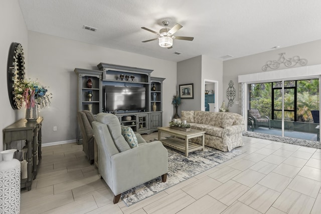 living room featuring ceiling fan and a textured ceiling