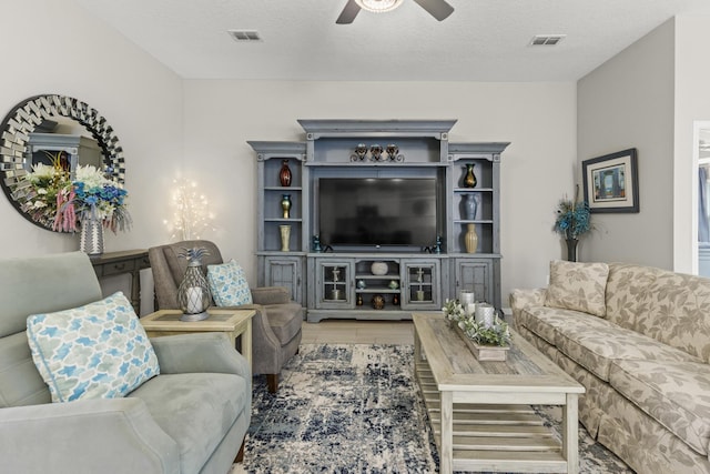 living room with hardwood / wood-style floors, a textured ceiling, and ceiling fan