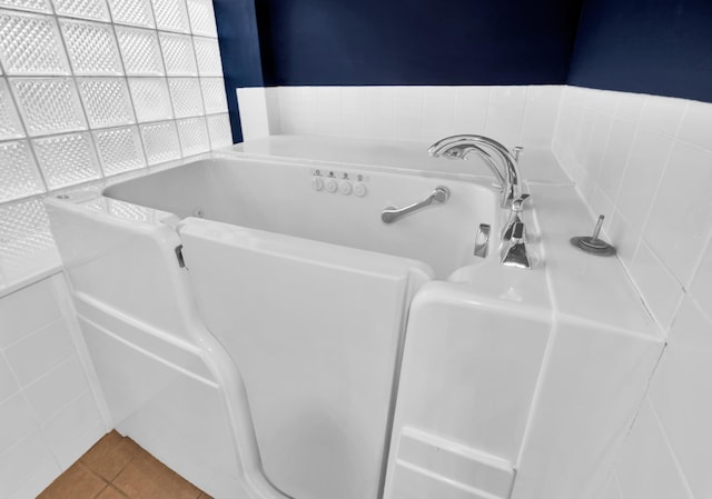 bathroom featuring a tub, tile patterned flooring, and tile walls