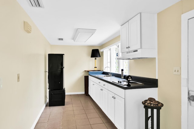 12 E Park Ave, Saint Augustine, FL 32084 - kitchen featuring under cabinet range hood, dark countertops, white cabinetry, light tile patterned floors, and cooktop