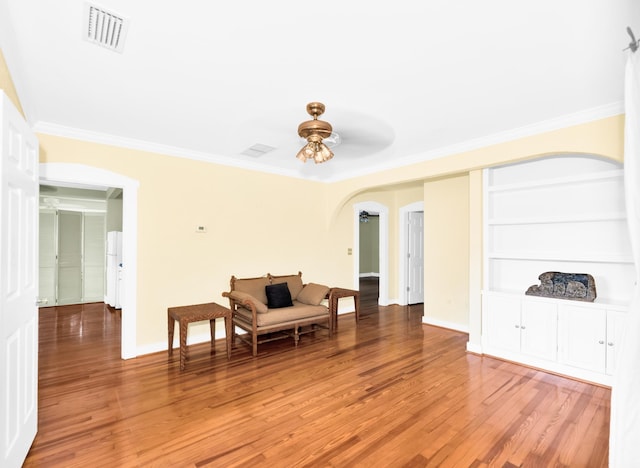 living area with hardwood / wood-style floors, ceiling fan, and crown molding