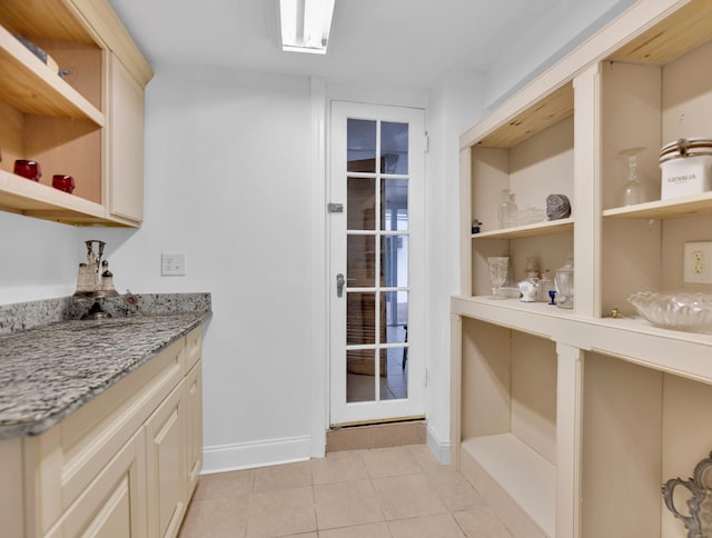 bar with light stone countertops, light tile patterned floors, and cream cabinets