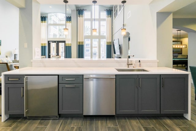 kitchen with appliances with stainless steel finishes, decorative light fixtures, sink, and gray cabinetry