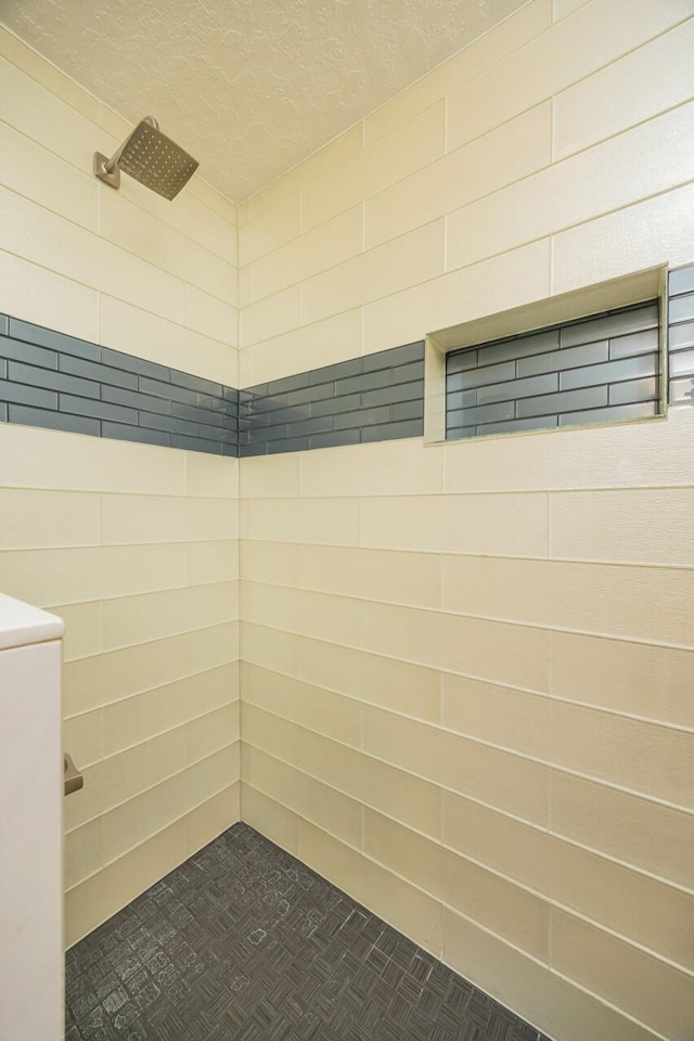 bathroom with tiled shower and a textured ceiling