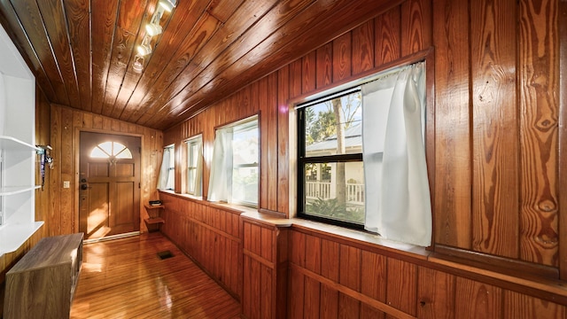 hallway featuring hardwood / wood-style flooring, lofted ceiling, wooden walls, and wooden ceiling