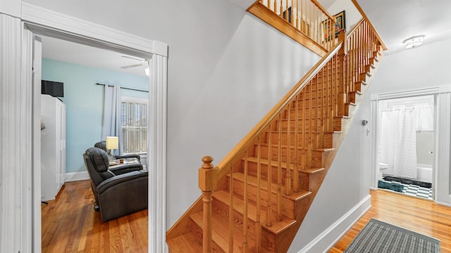 stairs with hardwood / wood-style flooring and ceiling fan