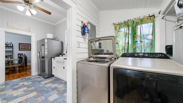 clothes washing area featuring crown molding, wooden walls, washing machine and dryer, and ceiling fan