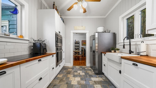 kitchen with butcher block countertops, sink, white cabinets, and appliances with stainless steel finishes