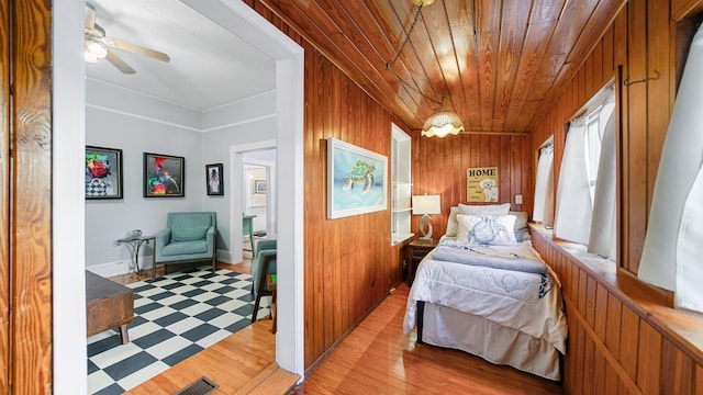 bedroom with wooden ceiling, light wood-type flooring, and wood walls