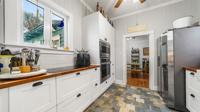 kitchen with appliances with stainless steel finishes, butcher block counters, ornamental molding, white cabinets, and decorative backsplash