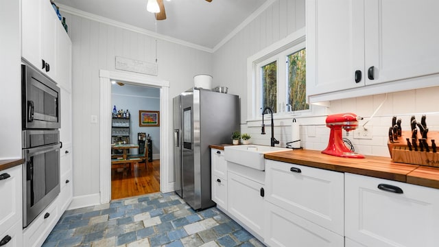 kitchen with sink, butcher block countertops, white cabinetry, crown molding, and appliances with stainless steel finishes