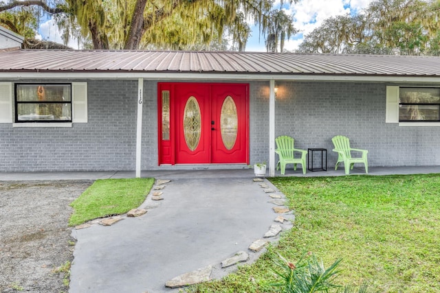 entrance to property with a porch and a yard