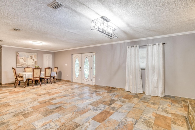 foyer entrance with ornamental molding, a textured ceiling, and french doors