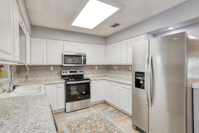 kitchen with sink, white cabinets, a textured ceiling, and appliances with stainless steel finishes