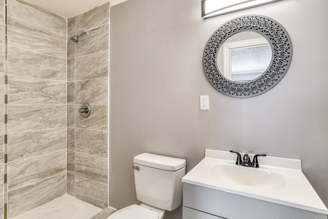 bathroom with tiled shower, vanity, and toilet