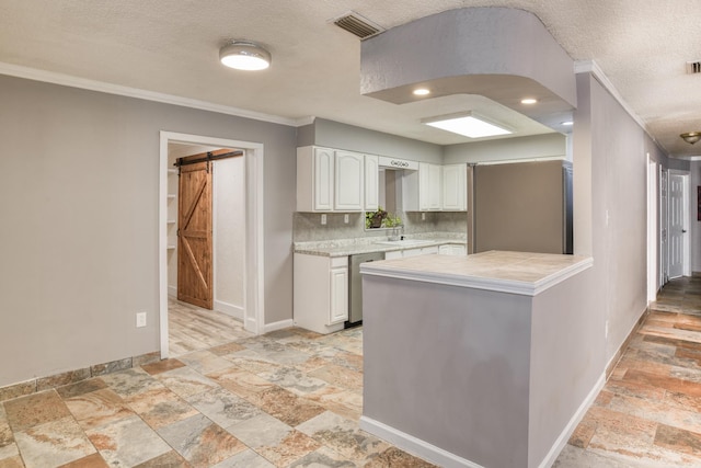 kitchen with kitchen peninsula, decorative backsplash, stainless steel dishwasher, a barn door, and white cabinetry