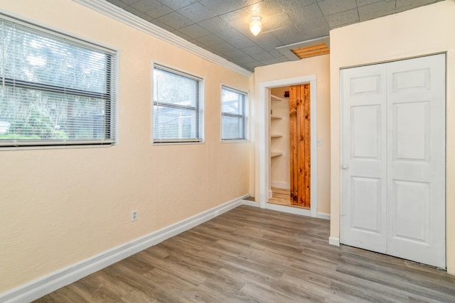 unfurnished bedroom with hardwood / wood-style floors, ornamental molding, and a closet