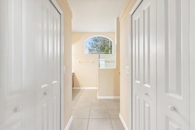 hall featuring light tile patterned floors and a textured ceiling