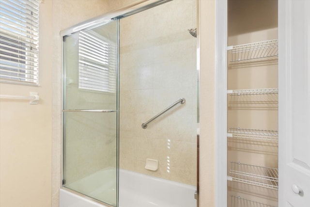 bathroom featuring plenty of natural light and bath / shower combo with glass door