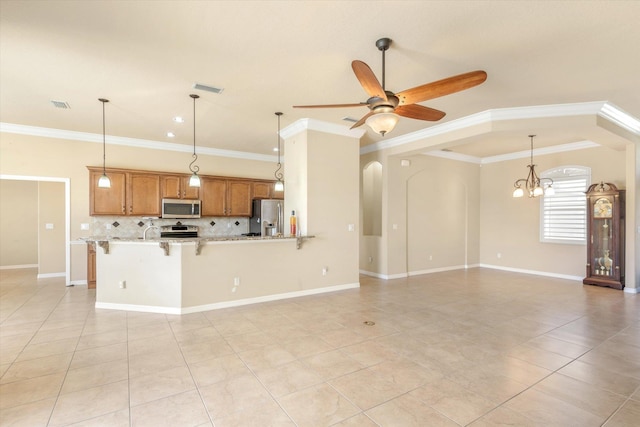 kitchen featuring light stone countertops, kitchen peninsula, decorative backsplash, appliances with stainless steel finishes, and ornamental molding