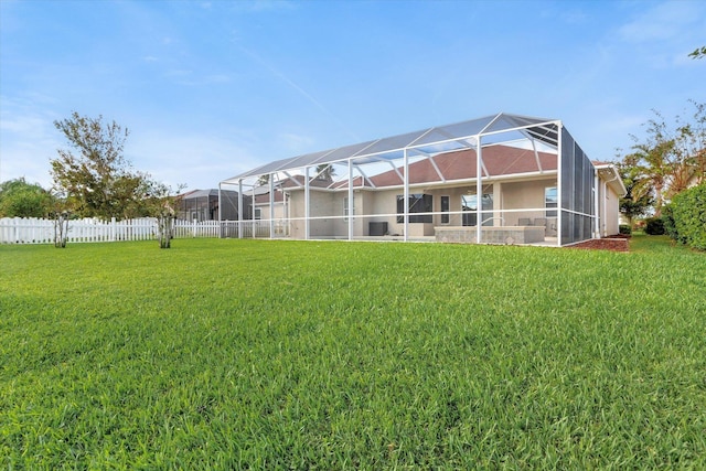 rear view of house featuring a yard and glass enclosure