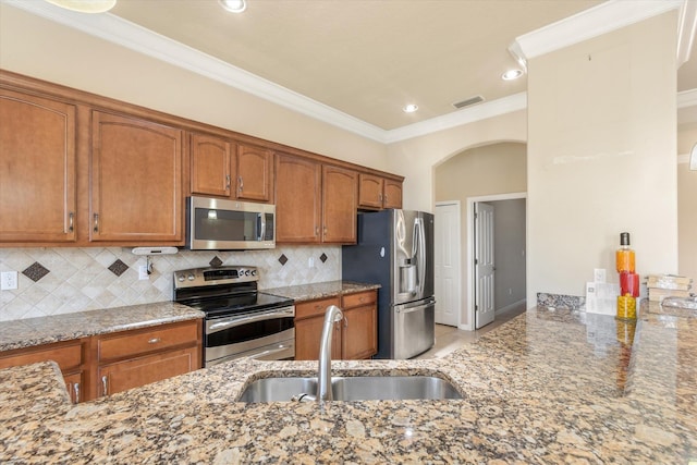 kitchen with stone counters, sink, decorative backsplash, ornamental molding, and appliances with stainless steel finishes