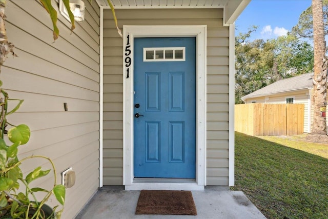 property entrance with a lawn and fence