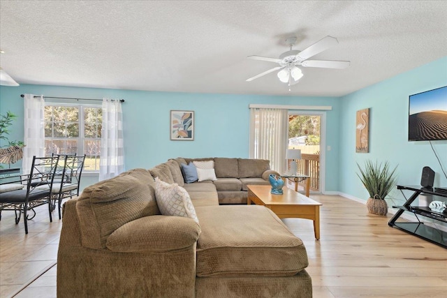 living area featuring plenty of natural light, a textured ceiling, and a ceiling fan