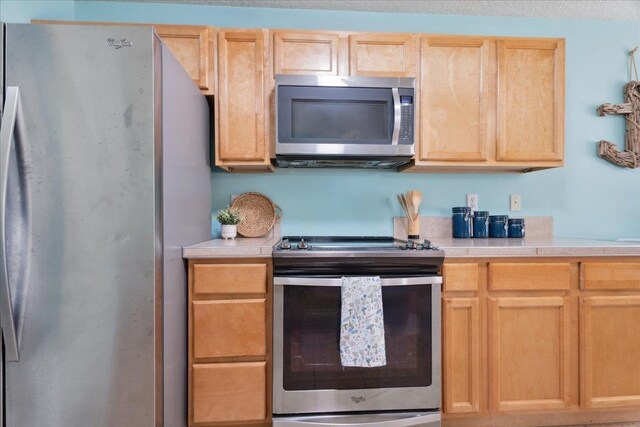 kitchen with stainless steel appliances, light brown cabinets, and light countertops