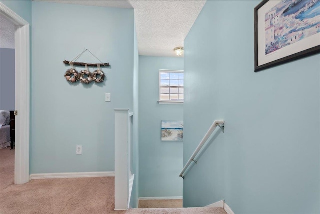 stairway featuring carpet, baseboards, and a textured ceiling