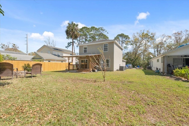 back of property with cooling unit, a lawn, and fence