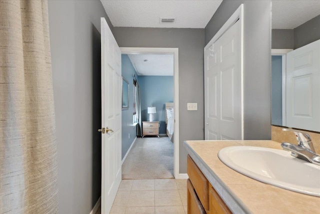 bathroom featuring tile patterned floors, visible vents, a textured ceiling, baseboards, and vanity