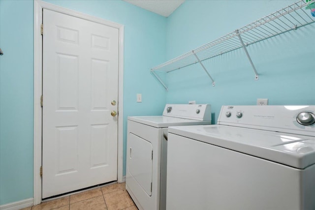 laundry area featuring light tile patterned floors, baseboards, laundry area, and washing machine and clothes dryer