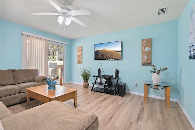 living room featuring a ceiling fan, light wood-style floors, visible vents, and baseboards