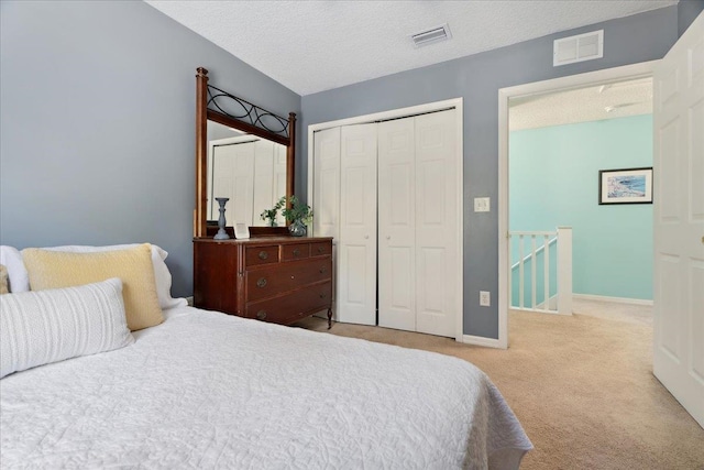 bedroom featuring carpet floors, visible vents, a closet, and a textured ceiling