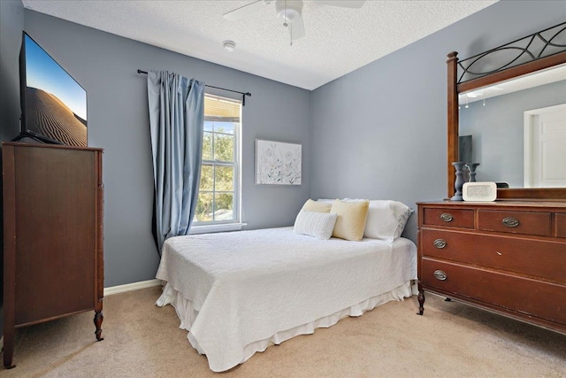 bedroom with light carpet, baseboards, a textured ceiling, and ceiling fan