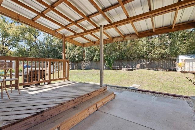 deck featuring a storage shed, a fenced backyard, a yard, an outbuilding, and a patio