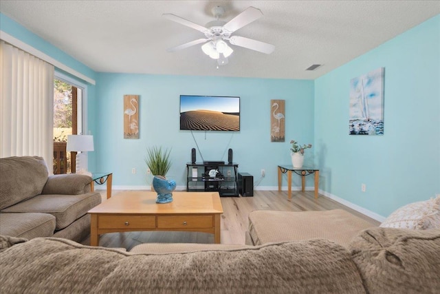 living room with visible vents, a textured ceiling, wood finished floors, baseboards, and ceiling fan