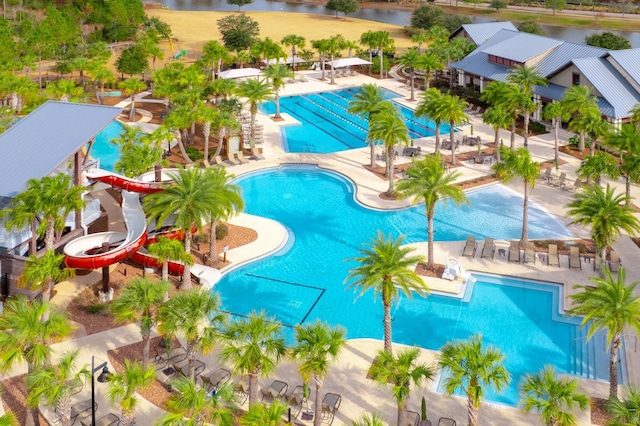 community pool featuring a patio, a water play area, a water slide, and a water view