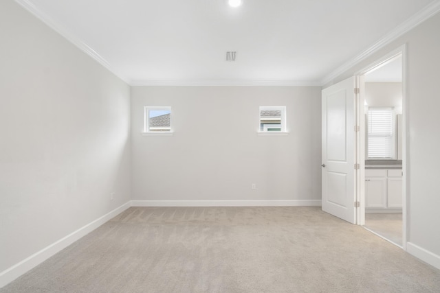 empty room with ornamental molding, light colored carpet, and a healthy amount of sunlight