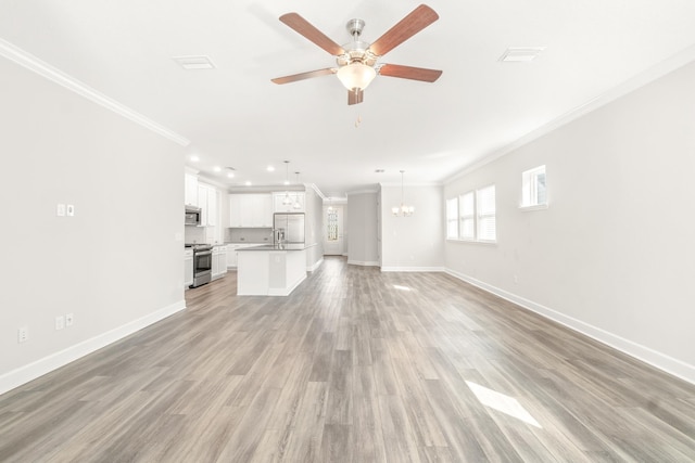 unfurnished living room featuring ceiling fan with notable chandelier, baseboards, crown molding, and light wood-style floors