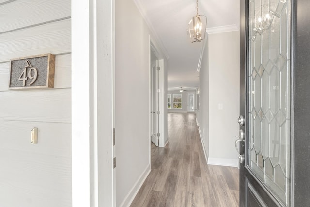 corridor featuring crown molding, baseboards, and wood finished floors