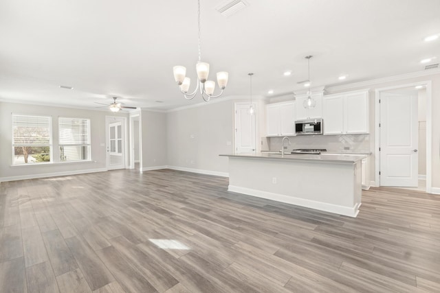 kitchen featuring white cabinetry, a kitchen island with sink, pendant lighting, and crown molding