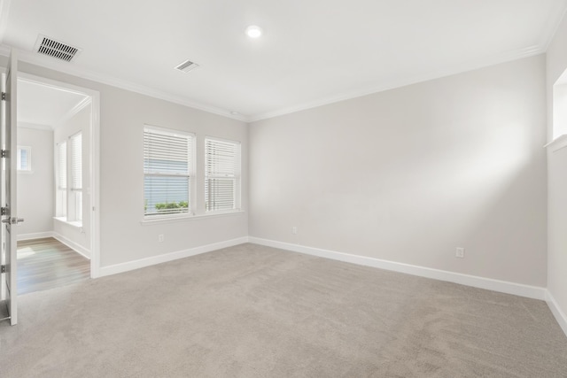 unfurnished room with light carpet, visible vents, baseboards, and ornamental molding