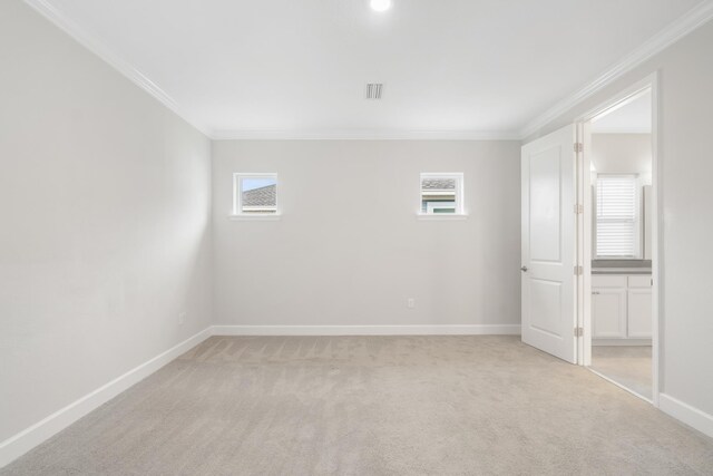 carpeted empty room featuring crown molding and plenty of natural light