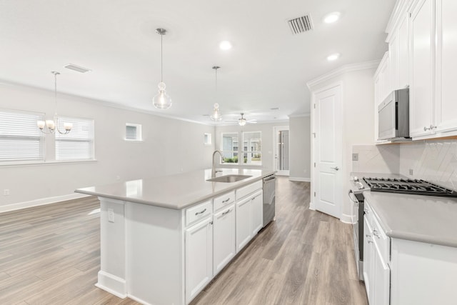 kitchen with tasteful backsplash, visible vents, crown molding, stainless steel appliances, and a sink